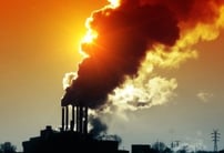 Image of a silhouette of smokestacks or steam towers at an industrial facility with the sun behind